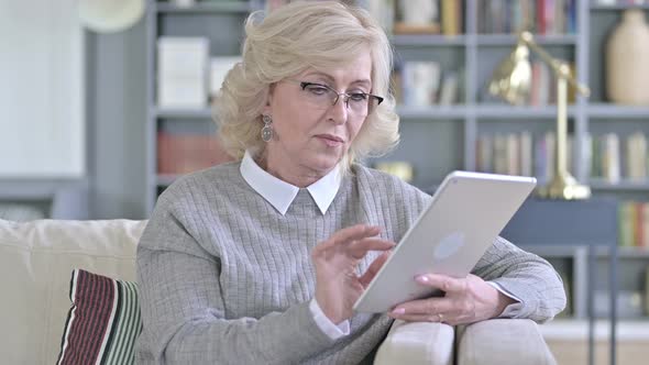 Old Woman Sitting on Sofa and Using Tablet