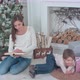 Mother Reading a Book for Her Little Son Lying Near Christmas Tree - VideoHive Item for Sale