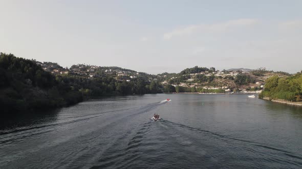 Fly over Rio Douro, motorboats cruising the calm flow of water, Castelo de Paiva, Portugal