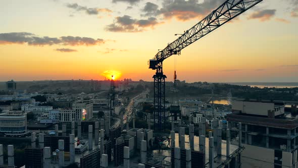 Construction Site at a Sunset. Urban Building Site and Cranes an the Sunset Cityscape alt