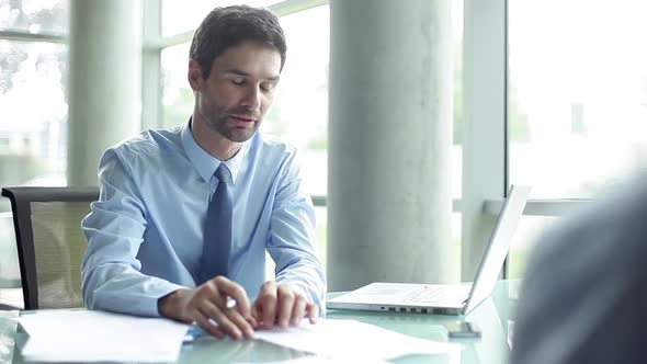 Businessman going over paperwork with client in office