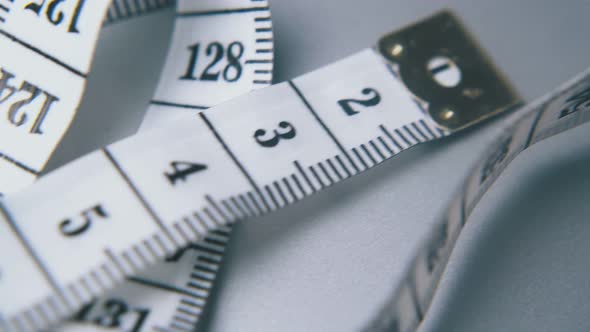 Soft Plastic Tape Measure Lies on Light Grey Surface Closeup