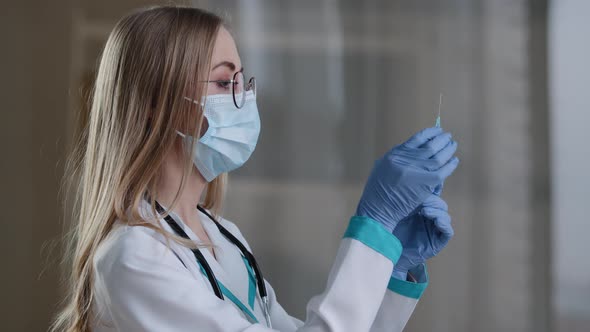 Woman Doctor Wearing a Face Mask and Medical Gown Preparing Holding Syringe for Injection Covid19