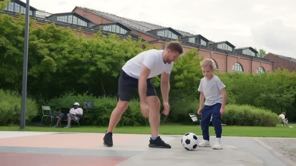 Happy Father and Little Son with Ball Playing Soccer at Summer Park