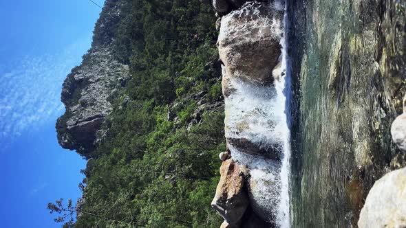 Mountain river water cascading through big wet stones creating small waterfalls. Vertical