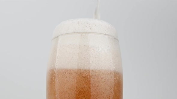 Close up pouring lager beer in glass over white