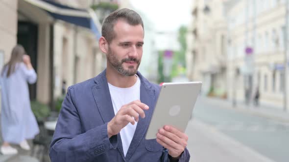 Mature Adult Man Celebrating on Tablet Outdoor