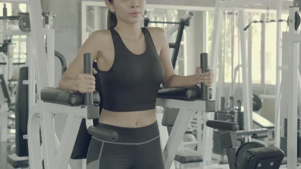 Young asian woman doing pull up exercise for bodybuilding of arm in the gym.