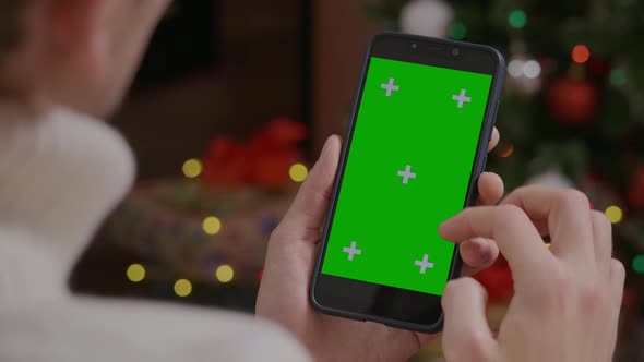 Close-up shot Green Screen Chroma key Smartphone in male hands in Christmas interior at home.