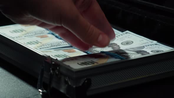 Counting American Hundred Dollar Banknotes Putting Money in Metallic Suitcase