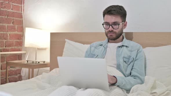 Ambitious Young Male Designer Working on Laptop in Bed