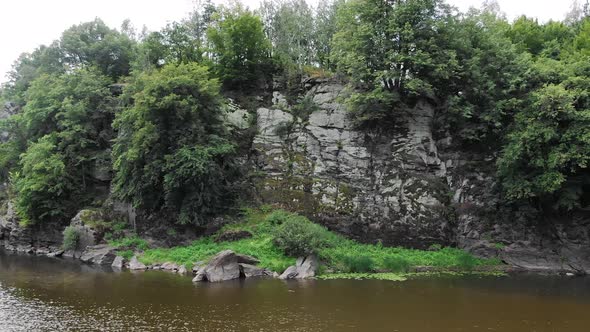 Aerial View of Steep Cliff on Rivers Edge With Thick Surrounded by Thick Forestry