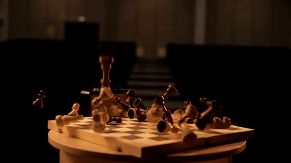 Wooden chess pieces fall on the chessboard in slow motion and crumble