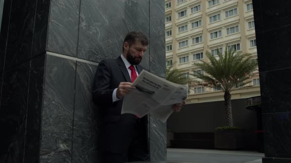 A Serious Middleaged Businessman in Luxurious Clothes in the Financial District of a Metropolis Uses