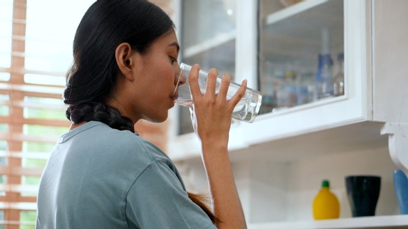 Young Asian woman drinking water and using tablets.