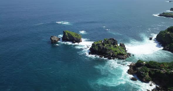 Aerial view showing blue colored ocean waves crashing against coral rocks at Timang Island,Indonesia