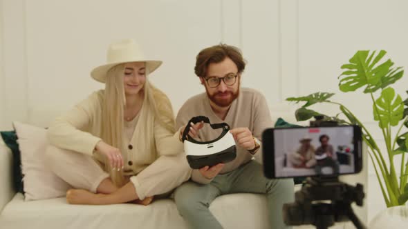 Young Cheerful European Influencers Creating a New Video While Sitting on a White Couch in Their