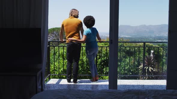 Rear view of mixed race couple enjoying the view while standing in the balcony at home