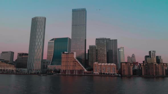 Low slider shot of Canary Wharf buildings along the Thames at sunset