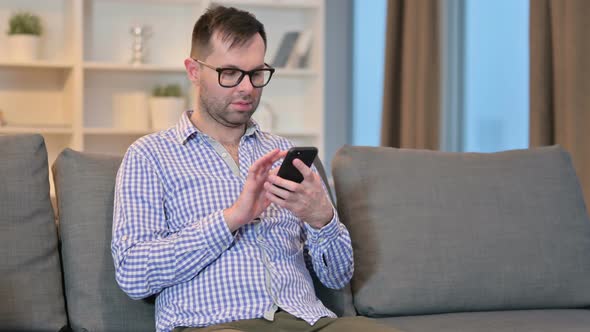 Attractive Young Man Using Smartphone at Home 