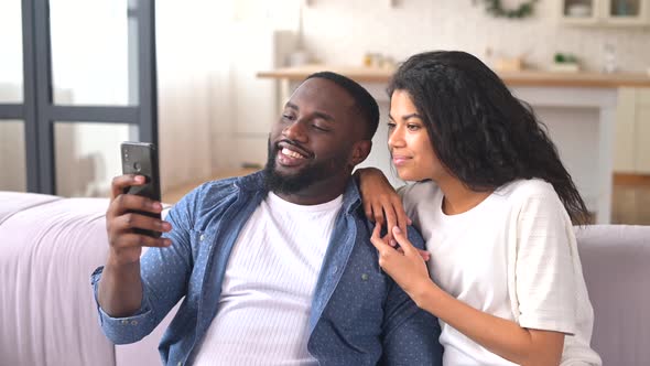 Happy Multiracial Couple Using a Smartphone at Home