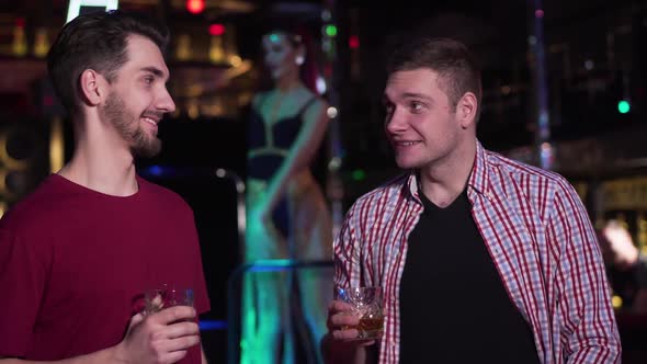 Two Handsome Caucasian Men Talking and Drinking Alcohol in Night Club, Young Positive