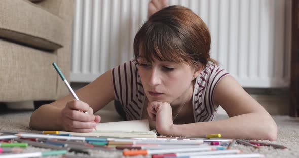 Portrait of woman drawing at home, laying on the floor