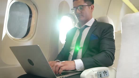 Young Businessman Using Laptop Computer in Airplane