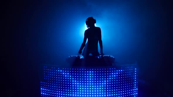 Seminude Blond Girl Dj Dancing and Mixes Music in Silhouette