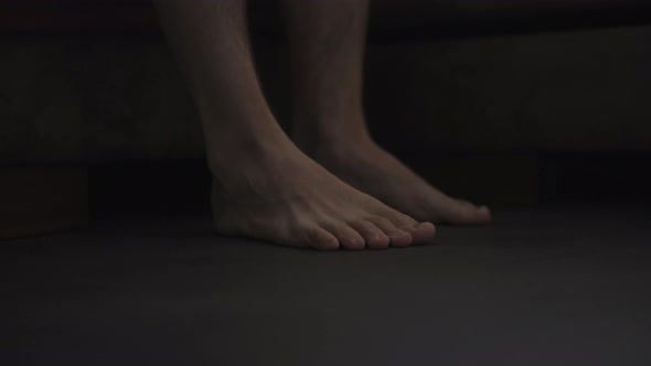 Dark Morning Shot of Man Feet on the Floor Near Bed