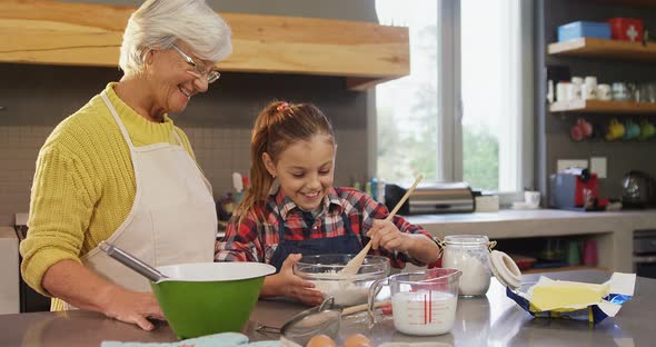 Grandmother watching the girl happily while mixing flour 4K 4k