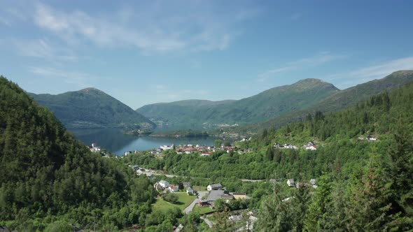 Ascending over dense fir pine trees Showing Vaksdal with road E16 and fjord with view over Osteroy