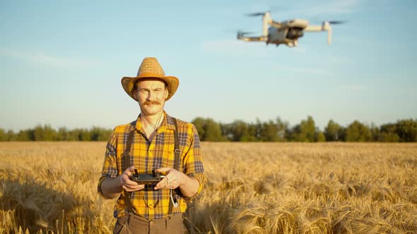 Caucasian Agronomist Male Explores a Wheat Field Flying a Drone in Sunset