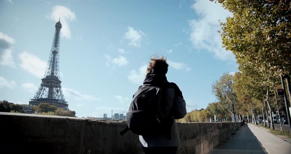 Tourist Girl with a Backpack Walks the City of Paris, Past the Eiffel Tower and the Seine River, and