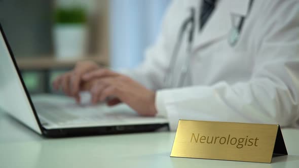 Male Neurologist in Uniform Typing on Laptop in Clinic, Keeping Medical Records