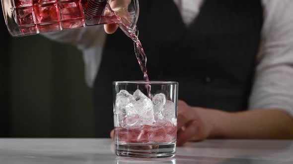 A Close-up in the Night Bar. The Bartender Pours the Finished Cocktail Into the Glass. A Beautiful