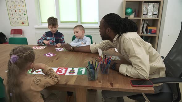 African American Teacher Teaches a Group of Children in a Classroom