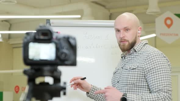 Teacher Records Video Lessons He Stands and Writes with a Pen on a Flip Chart