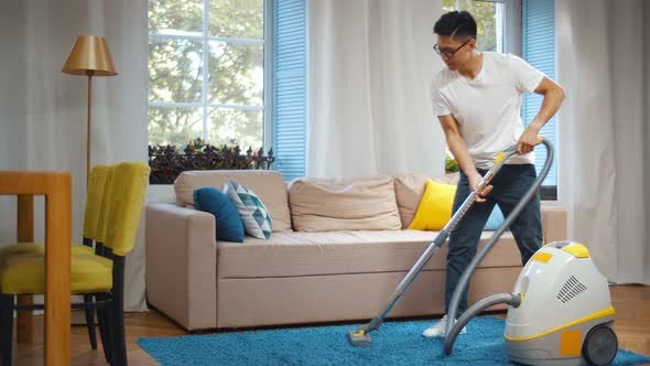 Young Asian Man Cleaning House with Vacuum Cleaner