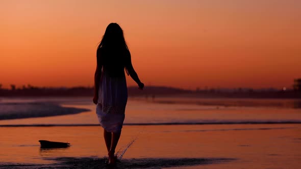 Asian woman enjoys a walk on the beach at sunset. Slow Motion.