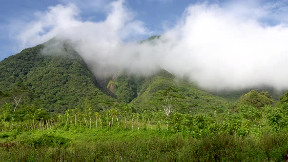 white puffy clouds covering the peak of a dormant volcano in Asia 4k