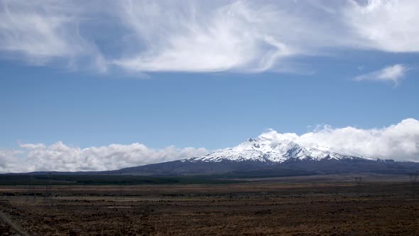 Wide establishing shot of Mount Ruapehu surrounded by beautiful clouds in New Zealand.