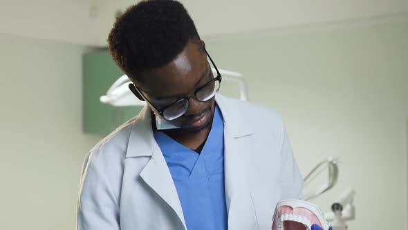 African Male Dentist Showing How to Clean Teeth with Toothbrush on a Plastic Model