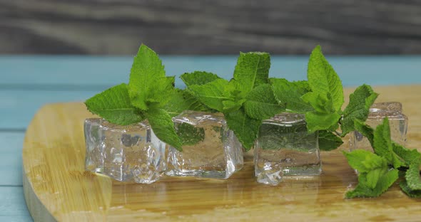 Ice Cubes and Mint Leaves Isolated on Wooden Cutting Board