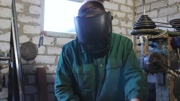 Professional Repairman in Protective Mask Working with Metal Details in Workshop