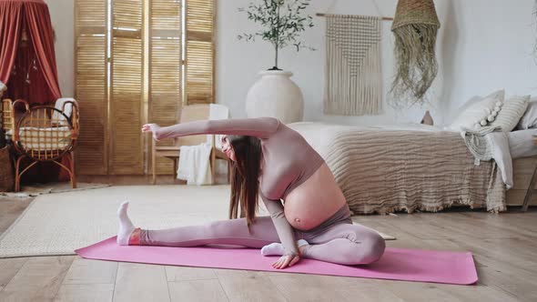 Young Pregnant Woman Enjoys Yoga Exercise on Pink Mat