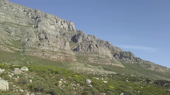 Aerial lower angle scenic drone flight view of Table Mountain in late afternoon sun against a blue s