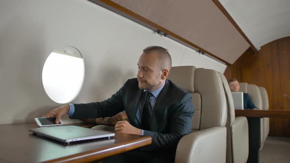 Confident Businessman in Formal Suit Travel on His Private Jet and Chat on Cell Phone