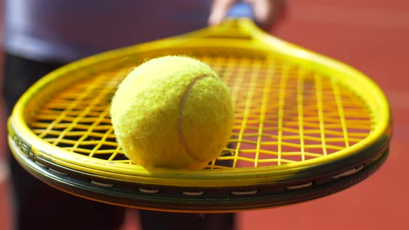 Male Hand Holding Tennis Racket with a Tennis Ball