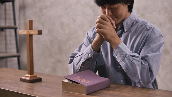 A young Christian man sitting in a church praying to God.